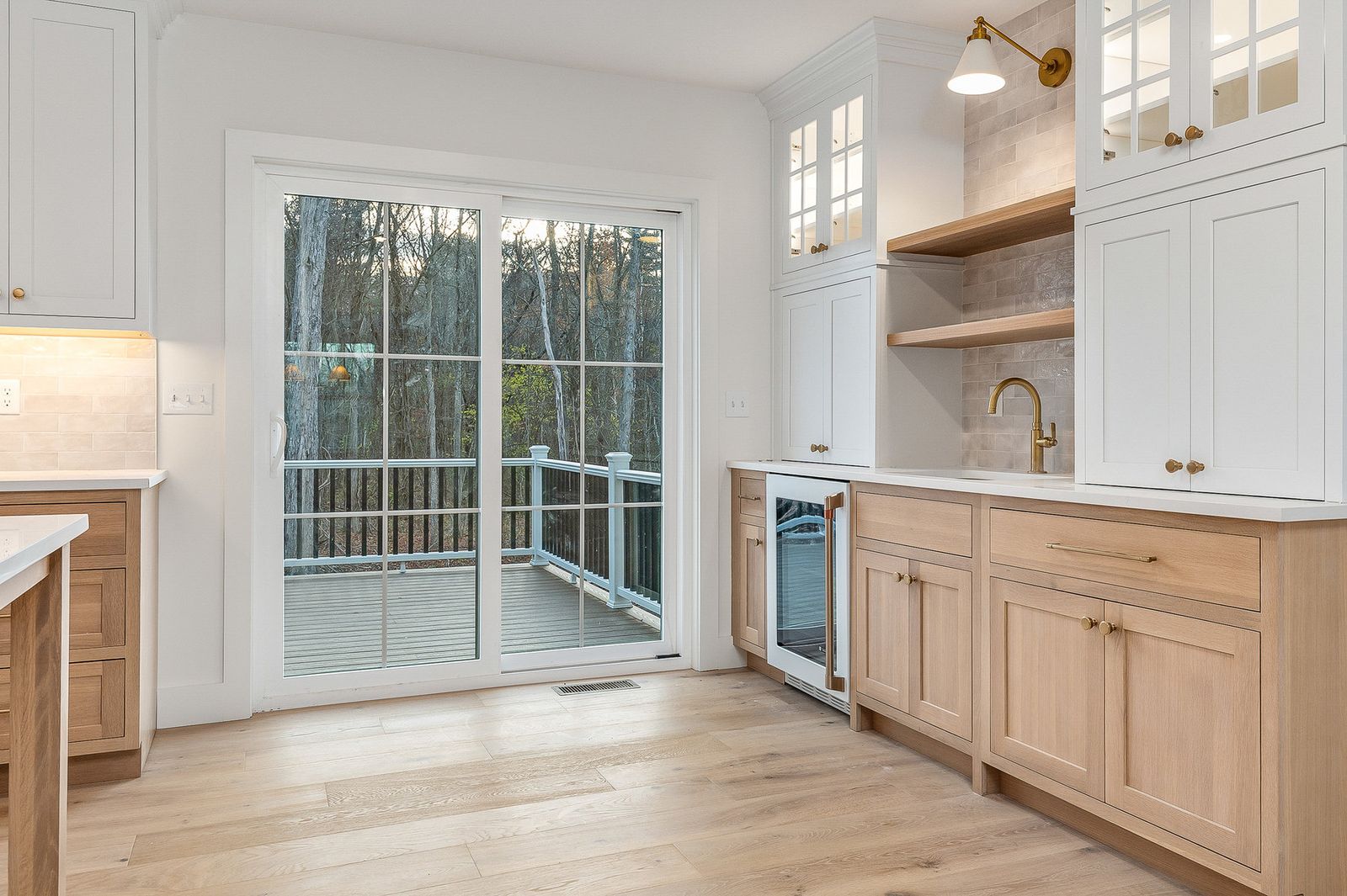 Kitchen corner with open oak shelving, a beverage refrigerator and sliding doors to the deck - a River Birch Builders home in the New Hampshire Seacoast