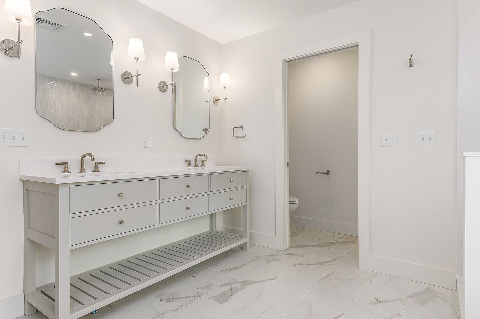 Double vanity bath with paired arched mirrors, wall sconces and marble tile floor - a River Birch Builders home in the New Hampshire Seacoast