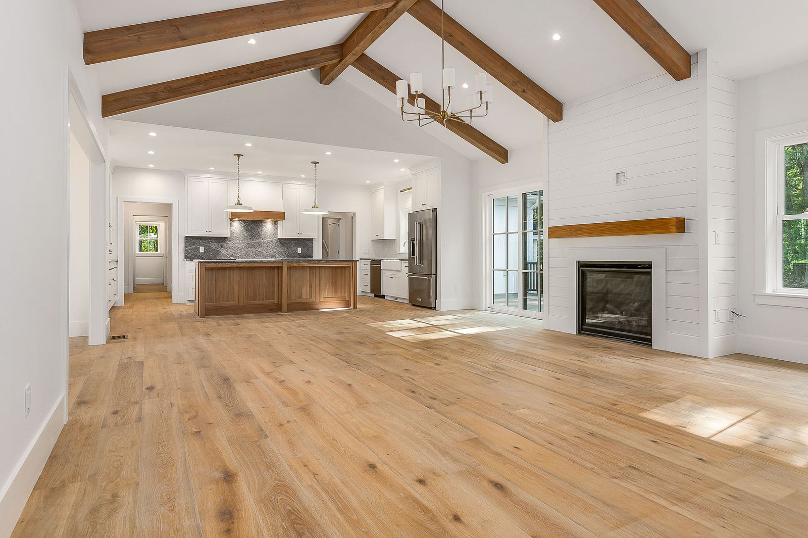 Great room with a vaulted beamed ceiling, fireplace and oak floors open to the kitchen - a River Birch Builders home in the New Hampshire Seacoast
