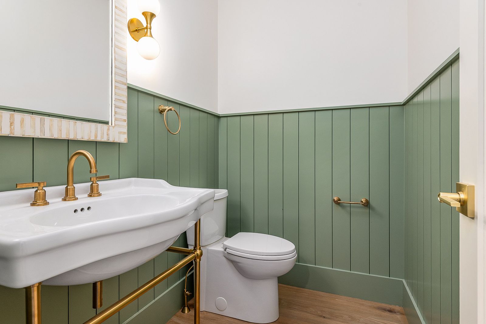 Powder room with green board-and-batten wainscoting and a console sink with brass fittings - a River Birch Builders home in the New Hampshire Seacoast