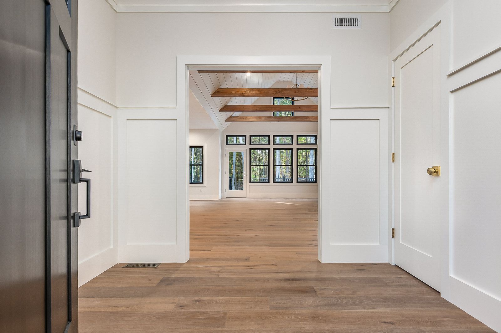 Entry hall with white trim and oak floors looking through to the living room - a River Birch Builders home in the New Hampshire Seacoast